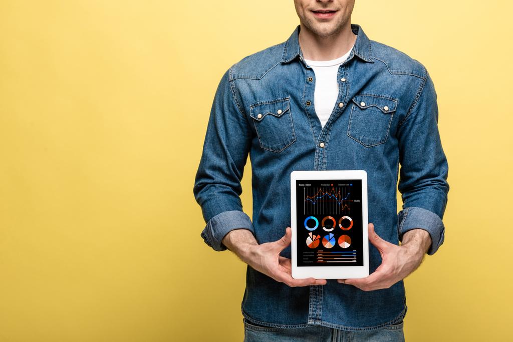 vágott kilátás az ember denim ruhát tartó digitális tabletta infographic app, elszigetelt sárga - Fotó, kép