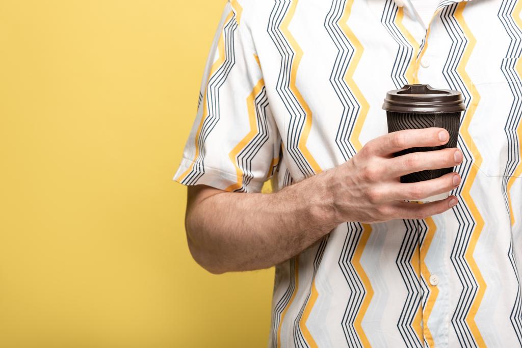 обрізаний вид людини в барвистій сорочці, що тримає одноразову чашку на жовтому фоні
 - Фото, зображення