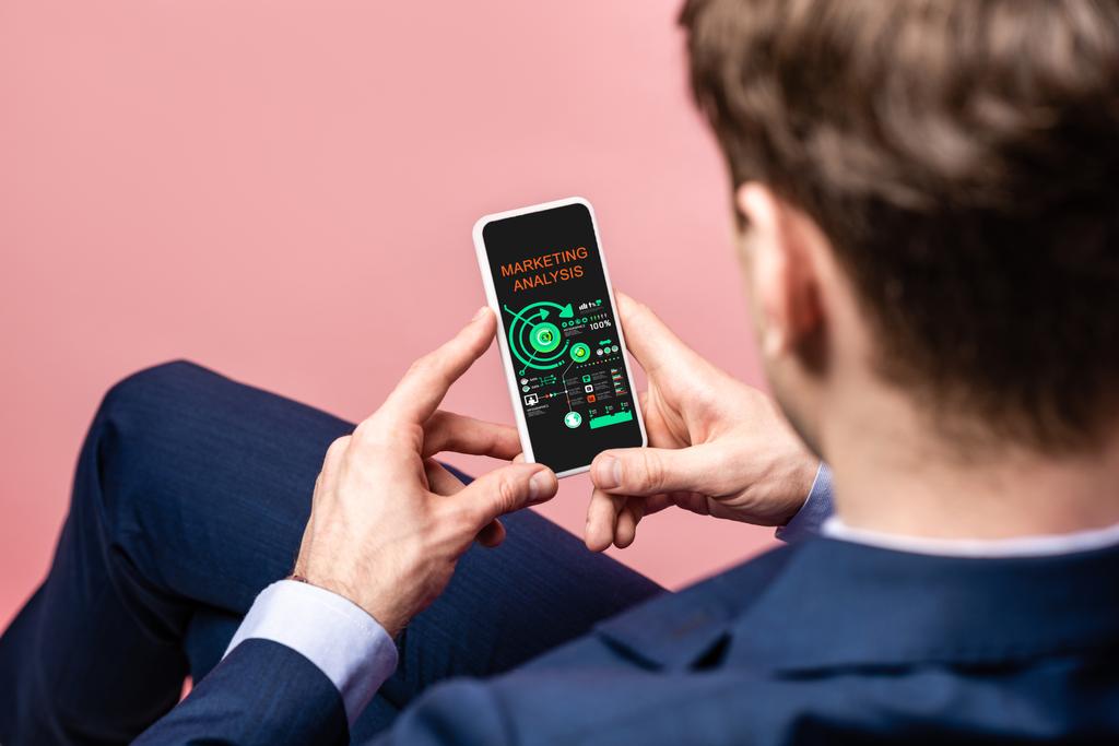 oříznutý pohled obchodníka pomocí telefonu Smartphone s marketingovou analýzou, izolovaný na růžovém - Fotografie, Obrázek
