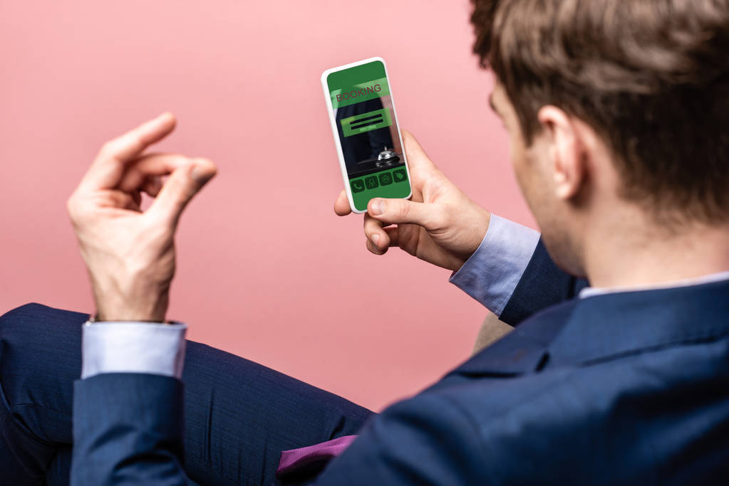 vue recadrée d'un homme d'affaires utilisant un smartphone avec application de réservation, isolé sur rose
 - Photo, image