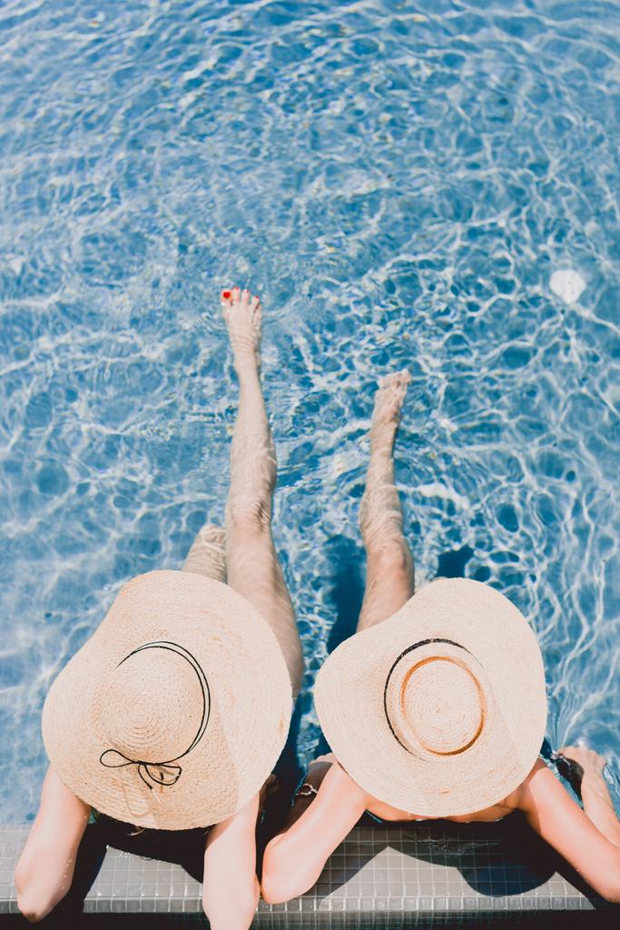 top view of two women in straw hats relaxing in swimming pool - Photo, Image