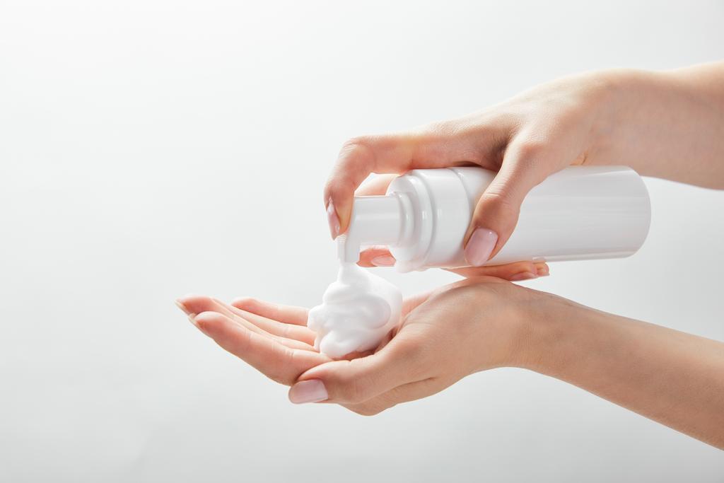vista recortada de la mujer usando dispensador cosmético con espuma aislada en blanco
 - Foto, imagen