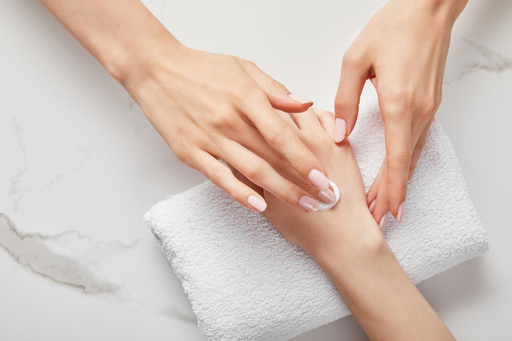 cropped view of woman applying cream on white surface with towel - Photo, Image
