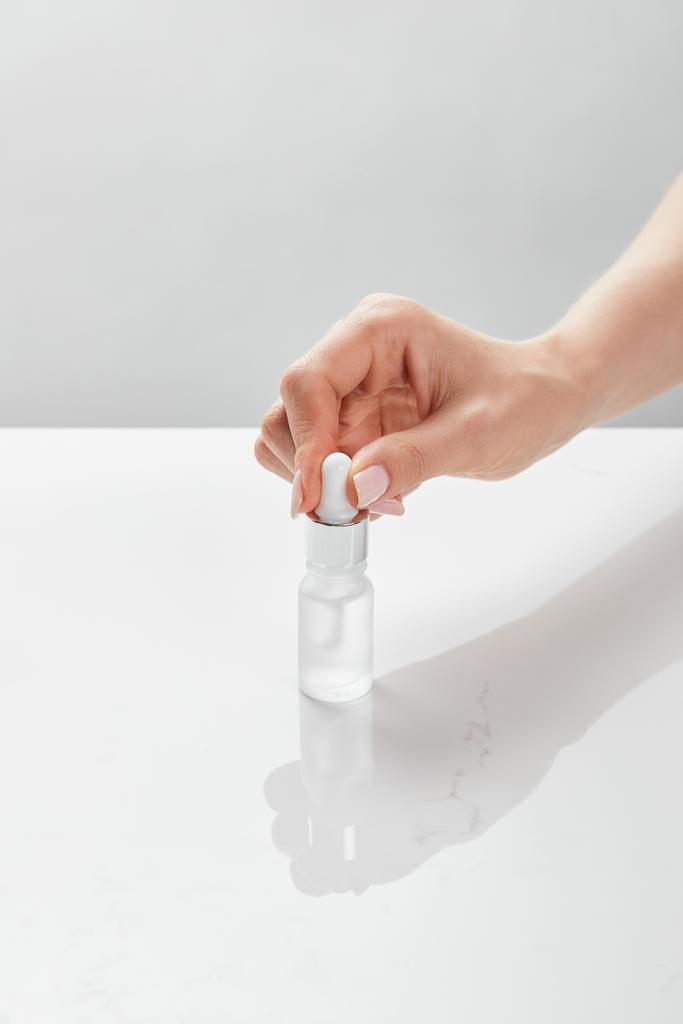vista recortada de la mano de la mujer con botella de vidrio cosmético
 - Foto, imagen