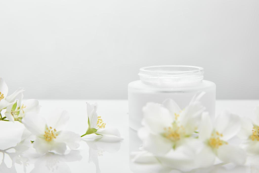 jasmíní květy na bílém povrchu u sklenice se smetanou - Fotografie, Obrázek