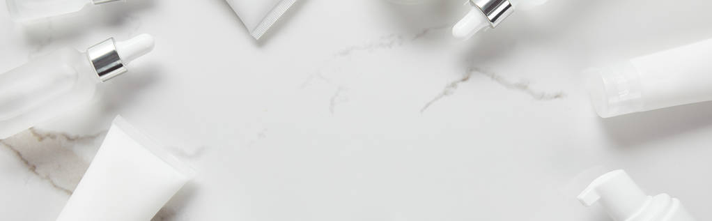 панорамний знімок косметичних скляних пляшок, трубок для зволоження та дозатора на білій поверхні
 - Фото, зображення