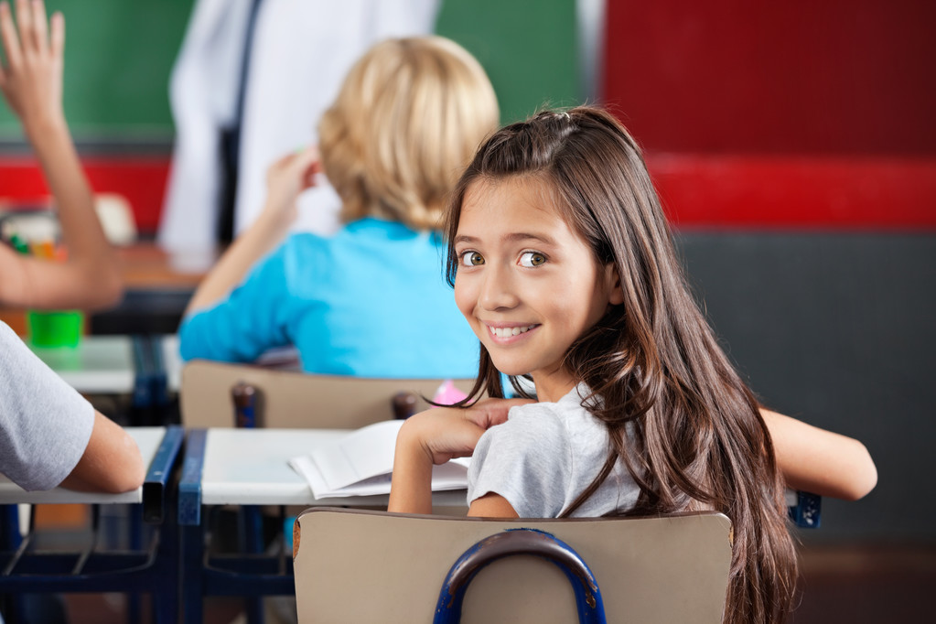 Écolière assise au bureau dans la salle de classe
 - Photo, image
