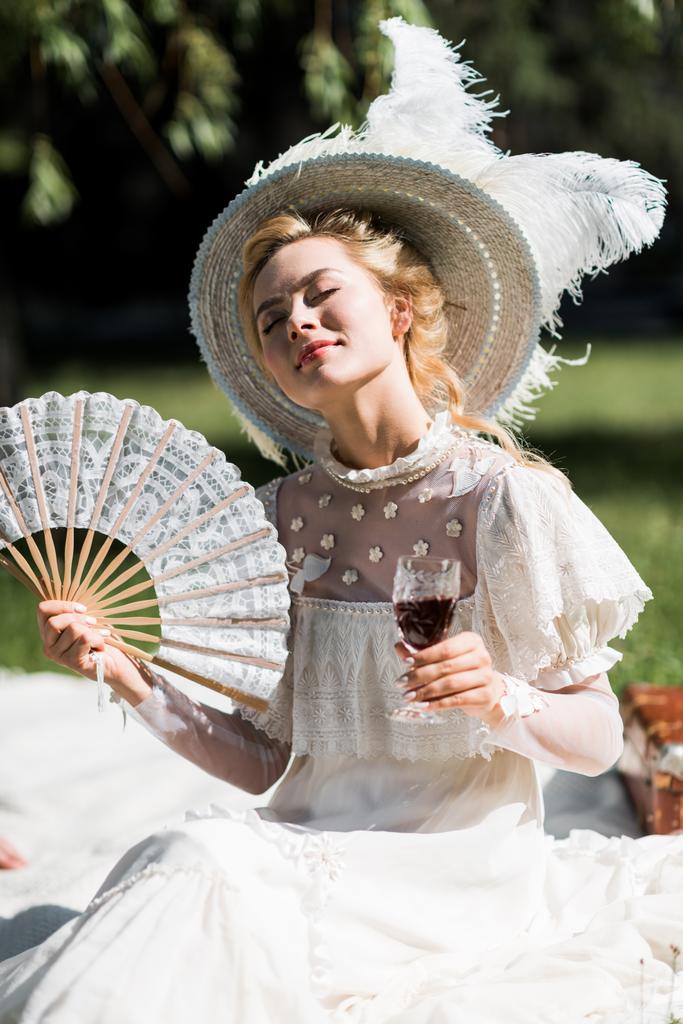 iloinen nuori viktoriaaninen nainen suljetuin silmin tilalla tuuletin ja viinilasi
  - Valokuva, kuva