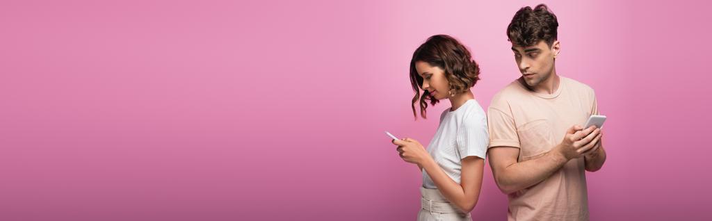 панорамный снимок молодого человека и женщины с помощью смартфонов на фиолетовом фоне
 - Фото, изображение