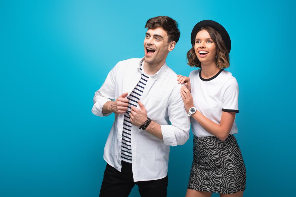 nuori, trendikäs mies ja nainen hymyilee ja katselee pois sinisellä taustalla
 - Valokuva, kuva