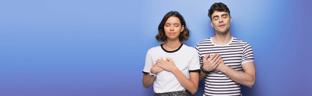 panoramic shot of pensive man and woman showing swear gestures on blue background - Photo, Image