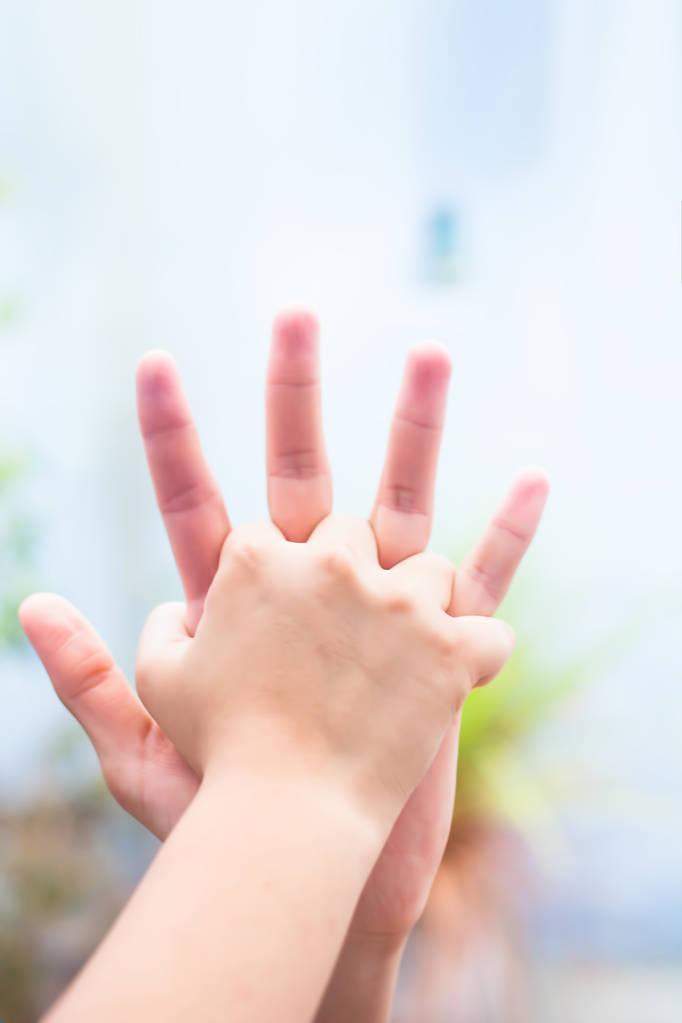 Kinderhand, die ihre Hand mit ihrem Vater vergleicht, aufgenommen mit verschwommenem Bokeh-Hintergrund und dem Konzept des Vatertags (16. Juni)).  - Foto, Bild