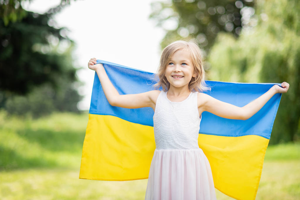 klein meisje uitvoering fladderende blauwe en gele vlag van Oekraïne in veld, Oekraïne Independence Day concept - Foto, afbeelding