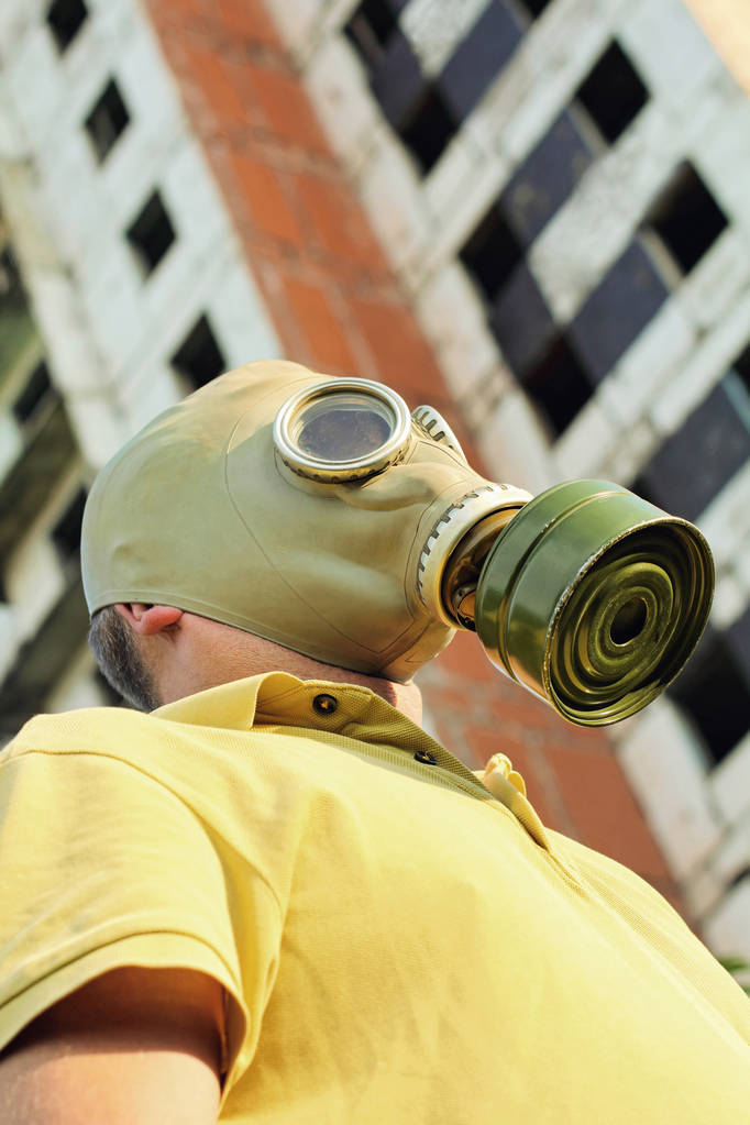 Persona con máscara de gas en el fondo del edificio destruido
. - Foto, imagen