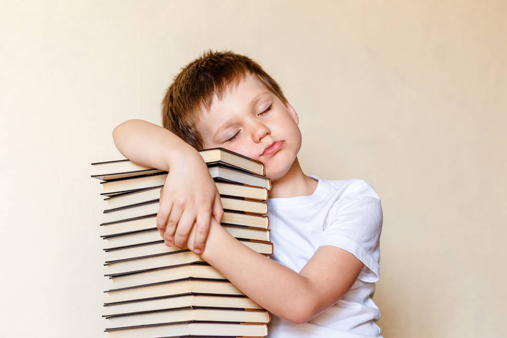 本の山の上で眠っている目を閉じた少年 - 写真・画像