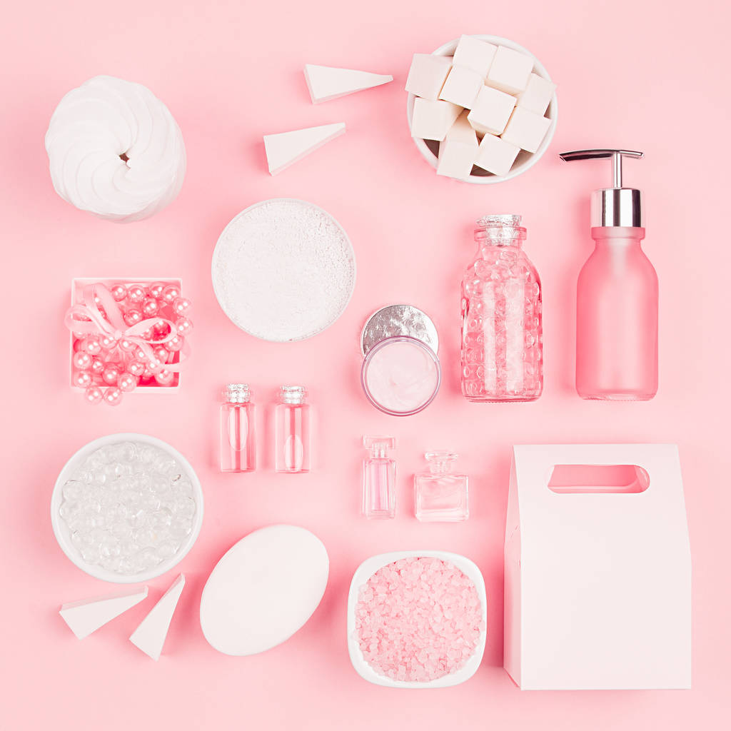 Cosmetic products for bathroom, health and hygiene in modern girlish style - decorative heart, soap, bath salt, essential oil, cream, towel, perfume, pearls, gift box on pink background, square. - Photo, Image