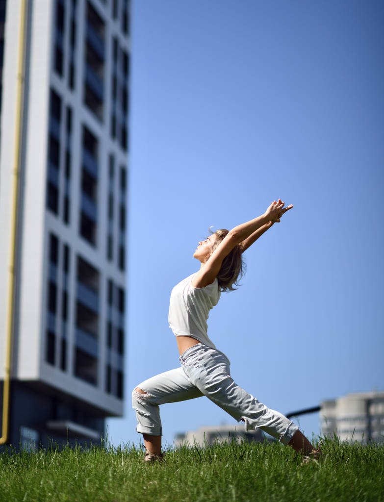 Nuori nainen tekee jooga venyttely harjoituksia kaupunkien moderni kaupunkipuisto
 - Valokuva, kuva