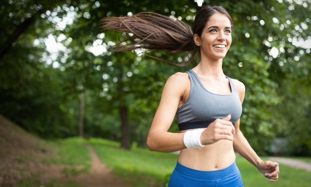 Young happy woman doing excercise outdoor in a park, jogging - Photo, Image