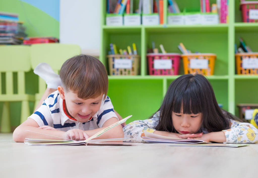 Deux gamins s'allongent sur le sol et lisent un livre de conte dans une chambre d'enfant.
 - Photo, image