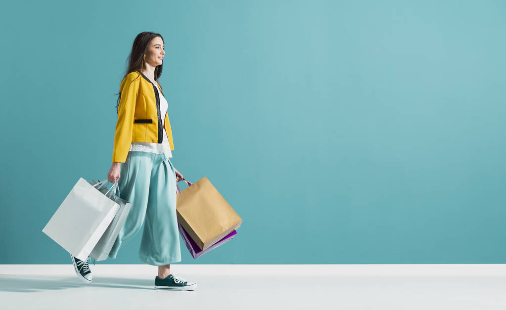 Sorrindo mulher andando e segurando sacos de compras
 - Foto, Imagem