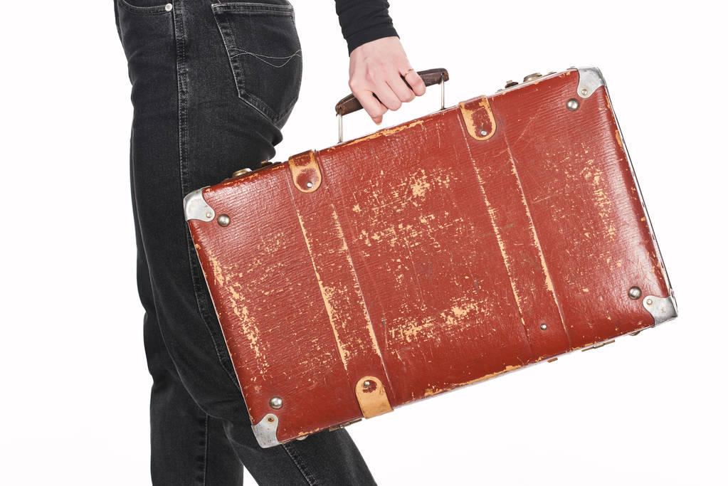 cropped view of girl in jeans holding vintage weathered suitcase isolated on white - Photo, Image