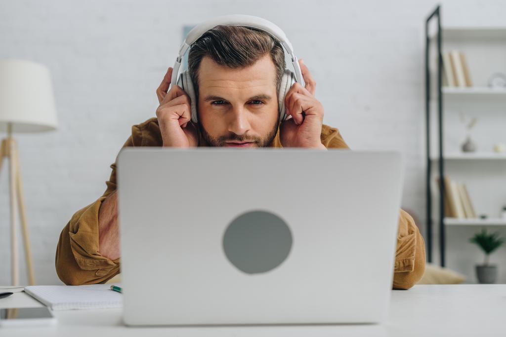 hombre guapo escuchando música y mirando la pantalla de la computadora portátil
  - Foto, Imagen