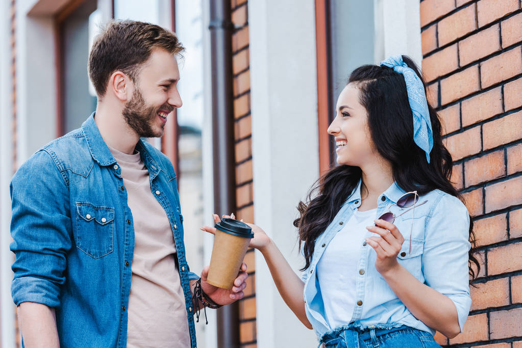 happy man giving paper cup to attractive woman while standing outside  - Photo, Image