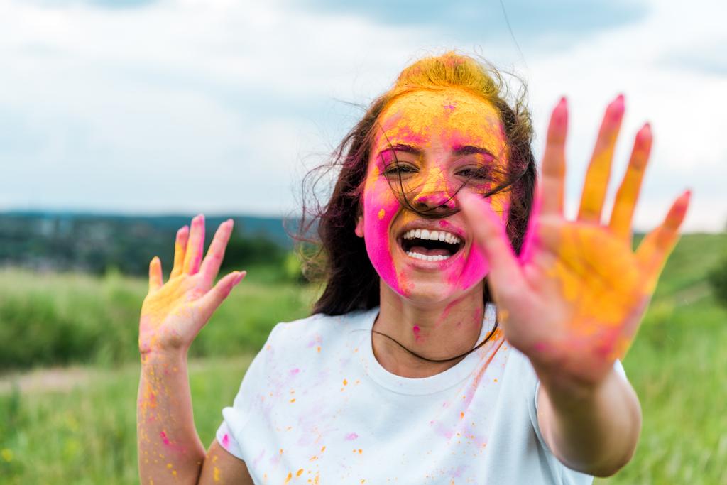 вибірковий фокус щасливої жінки з рожевою і жовтою фарбою на обличчі і руках
 - Фото, зображення