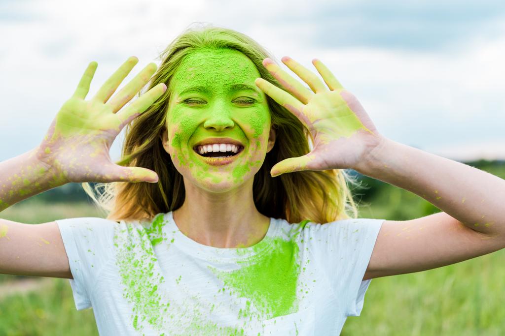 Veselá žena s zavřenýma očima a zelená holi malováním na rukou gestikulováním a usmívajícími se venku  - Fotografie, Obrázek
