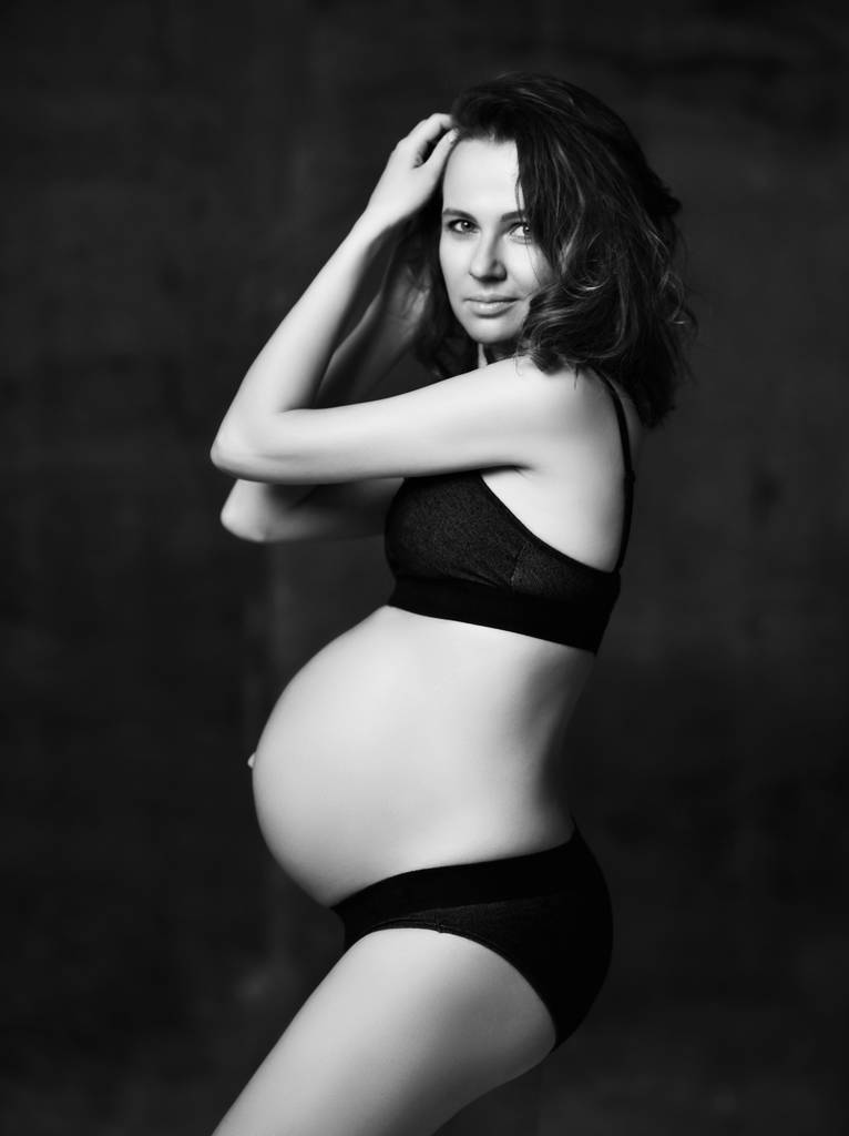 暗い背景にポーズ美しい若い妊娠中の幸せな母の女性 - 写真・画像