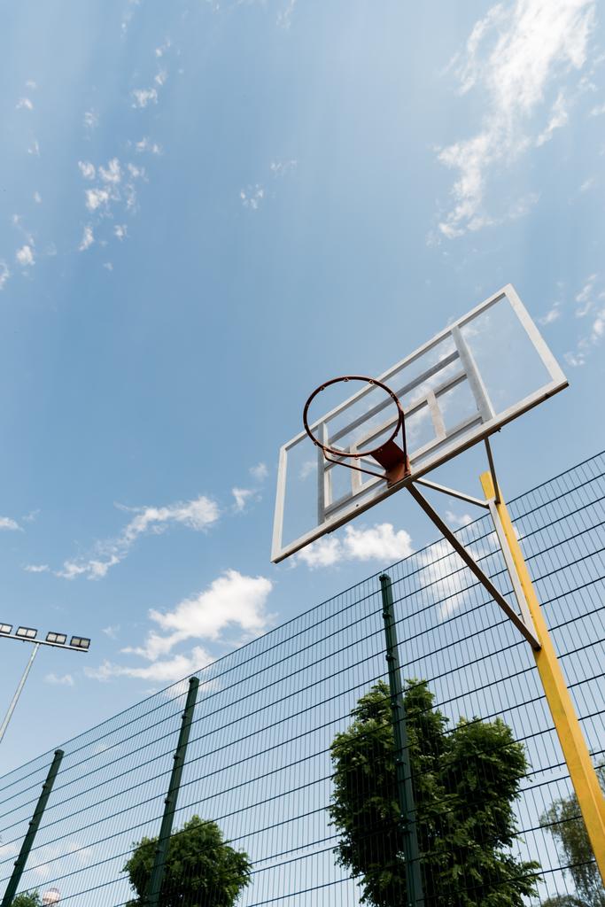 vista inferior del tablero de baloncesto bajo el cielo azul con nubes
 - Foto, Imagen