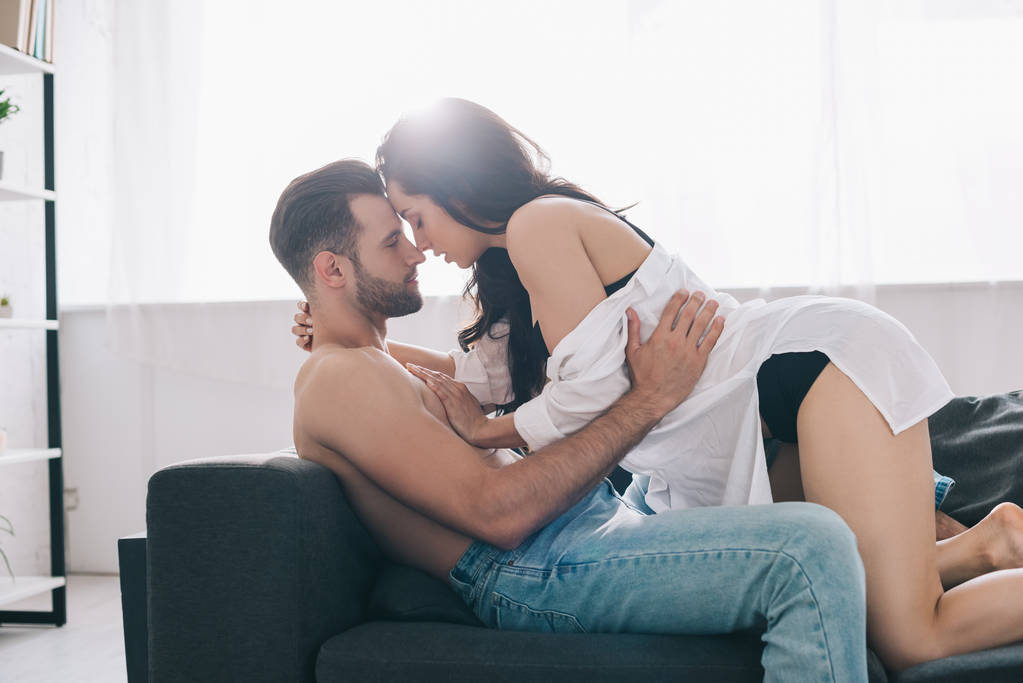 vue latérale d'un homme torse nu et beau embrassant et embrassant avec une femme brune
  - Photo, image