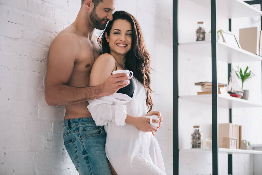bel homme et femme souriante en chemise tenant des tasses
  - Photo, image