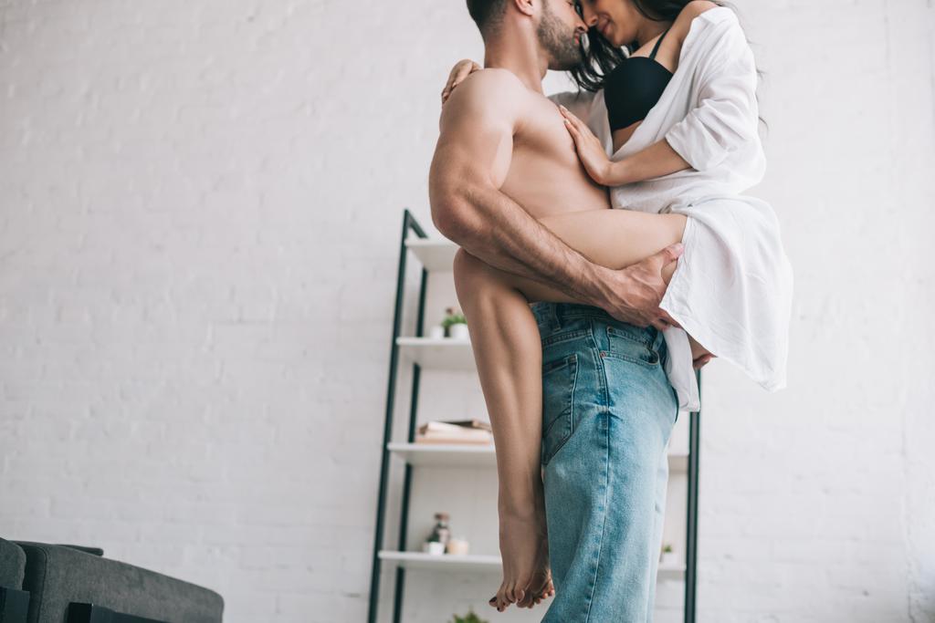 cropped view of man in jeans holding and kissing with sexy woman  - Photo, Image
