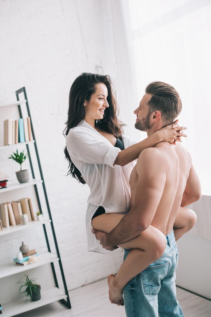 handsome man in jeans holding and hugging with sexy woman in shirt  - Photo, Image