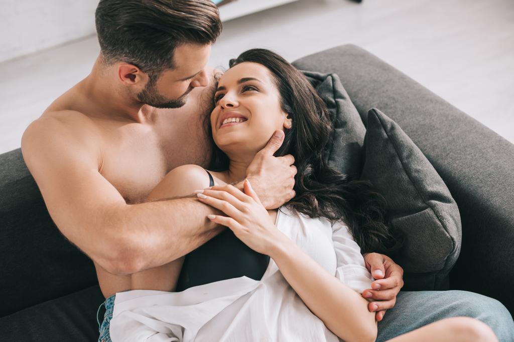 homem bonito e mulher sexy na camisa deitada no sofá e abraçando
  - Foto, Imagem
