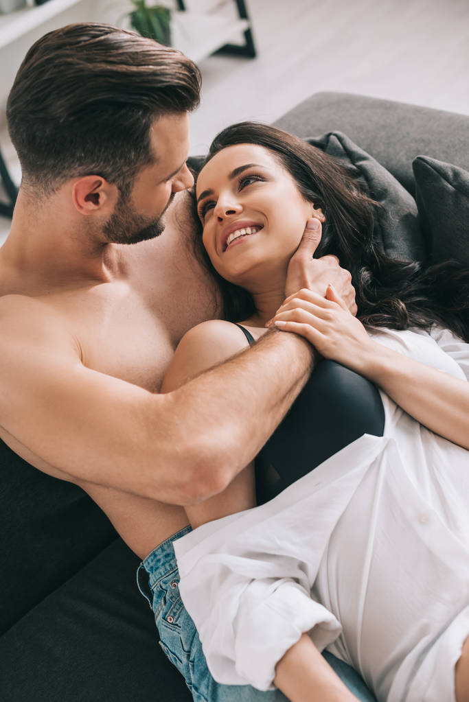 bell'uomo e donna sexy in camicia sdraiata sul divano e abbracciata
  - Foto, immagini