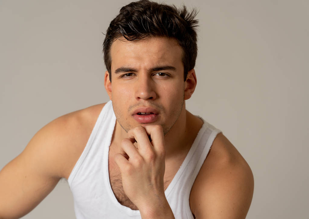 Portret młodego, atrakcyjny męski łaciński w jego 20s patrząc sexy stwarzające przed neutralne tło. Silny model fitness słodki i męski na tle neutralnym. Koncepcja ludzi i urody. - Zdjęcie, obraz