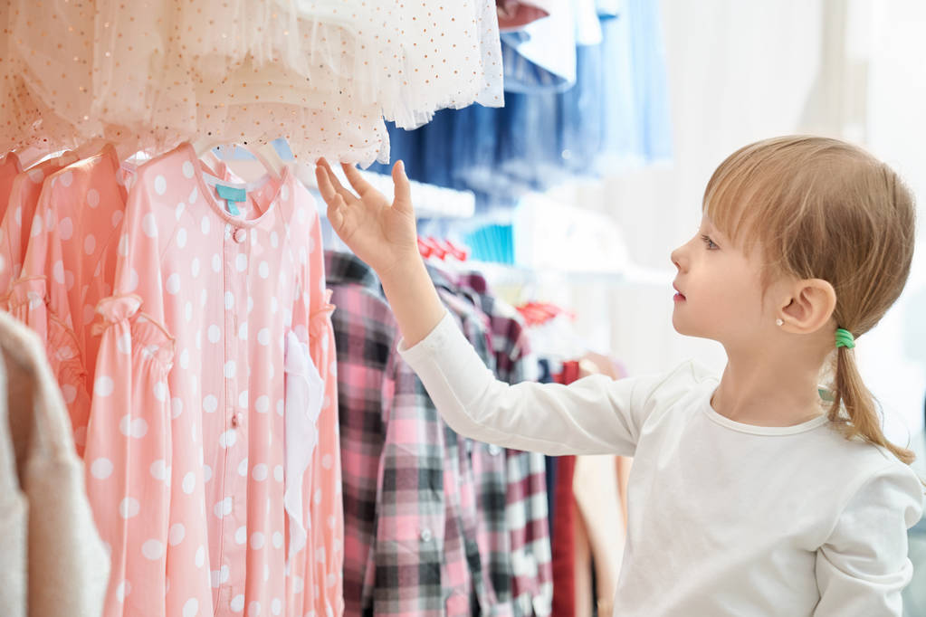 Menina engraçada olhando para lindo vestido rosa na loja
 - Foto, Imagem