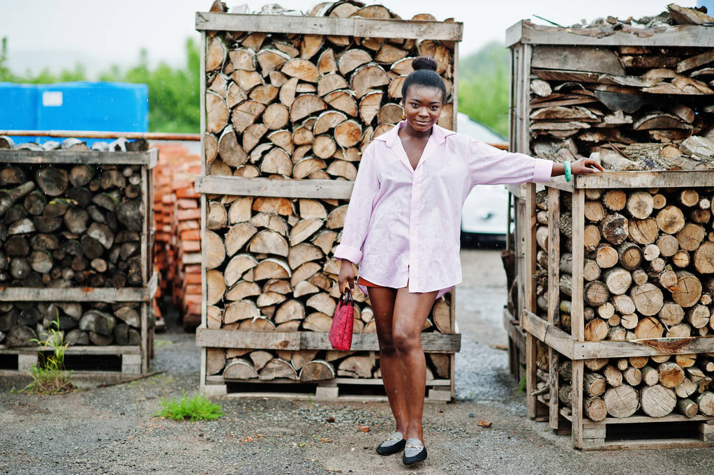 Африканська жінка в рожевому велику сорочку позувала під дерев'яні. - Фото, зображення