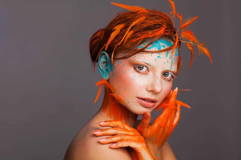 Portret pięknego modelu z kreatywnym makijażu i fryzurą za pomocą pomarańczowych piór - Zdjęcie, obraz