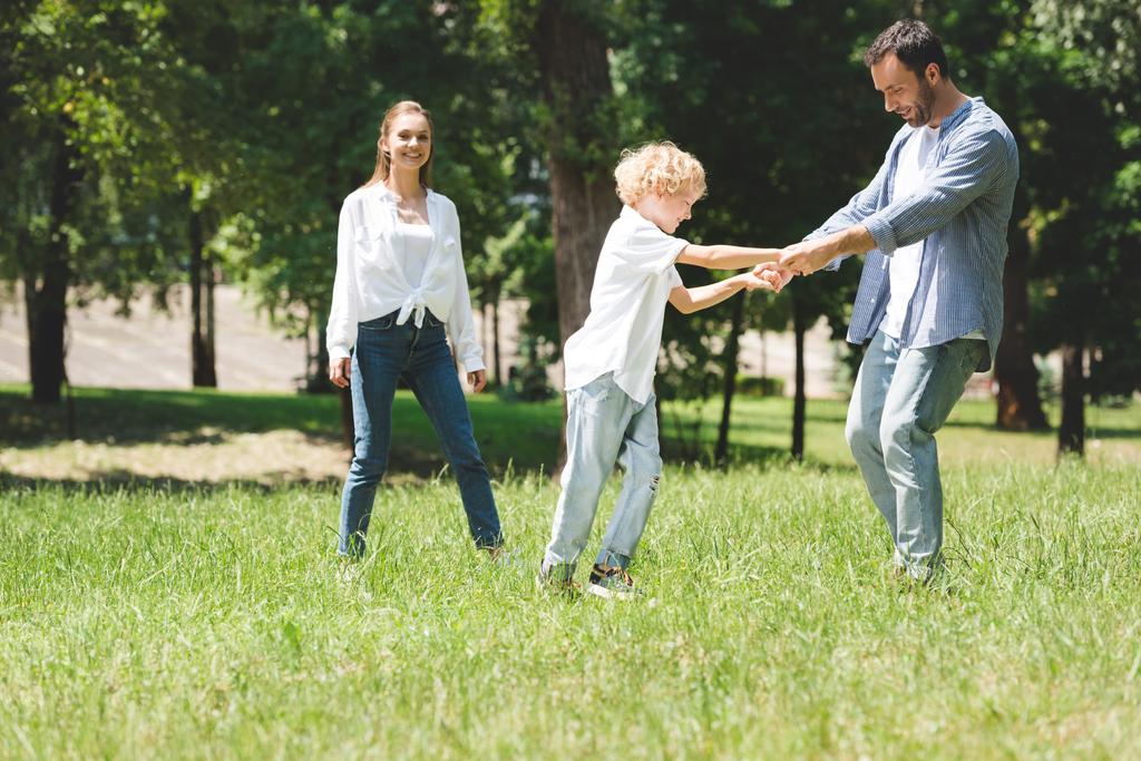 οικογένεια περνά χρόνο μαζί, πατέρας κρατώντας τα χέρια με το γιο στο πάρκο - Φωτογραφία, εικόνα