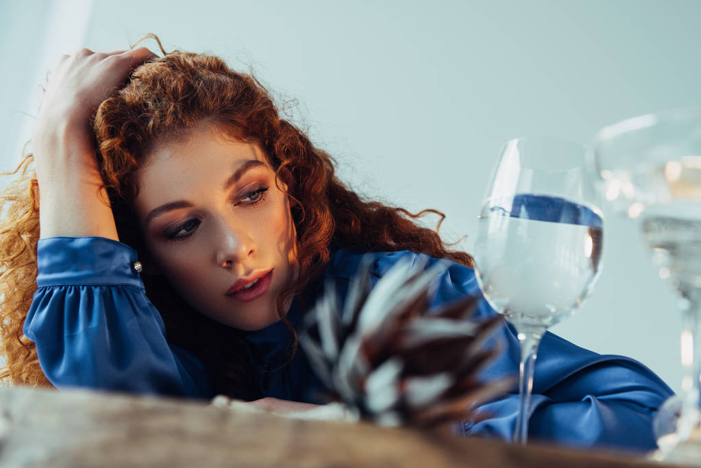 beautiful stylish redhead woman posing near glasses with water isolated on grey - Photo, Image