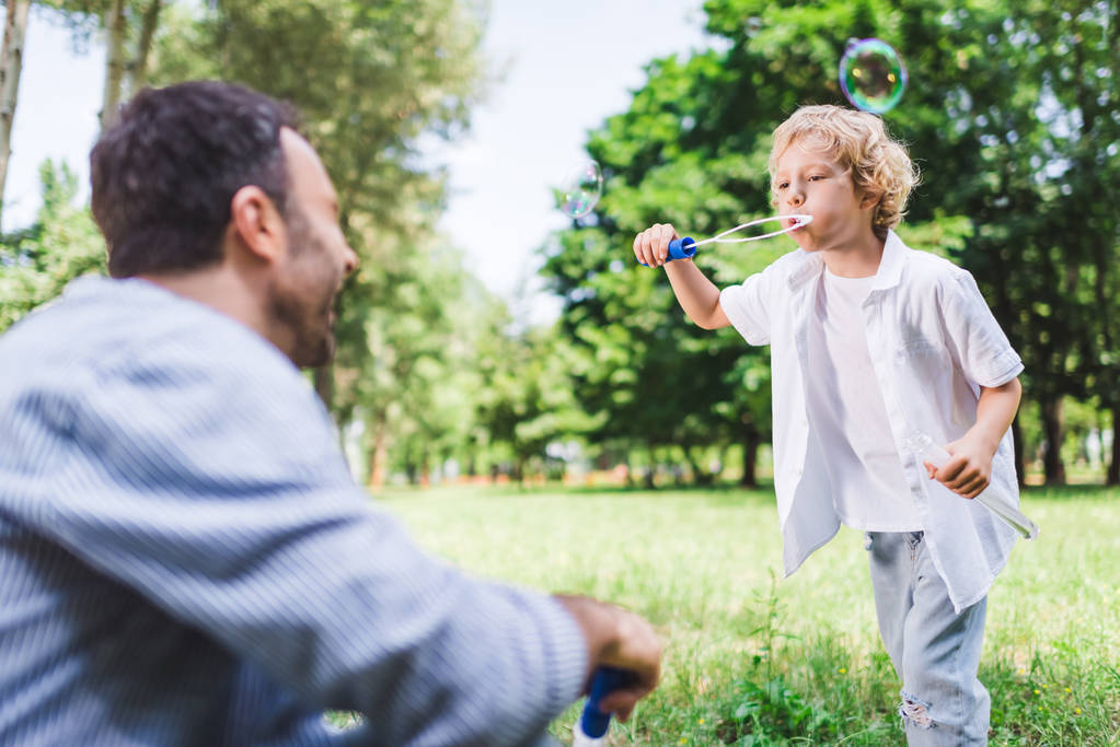 батько і чарівний син грає з мильними бульбашками в парку
 - Фото, зображення