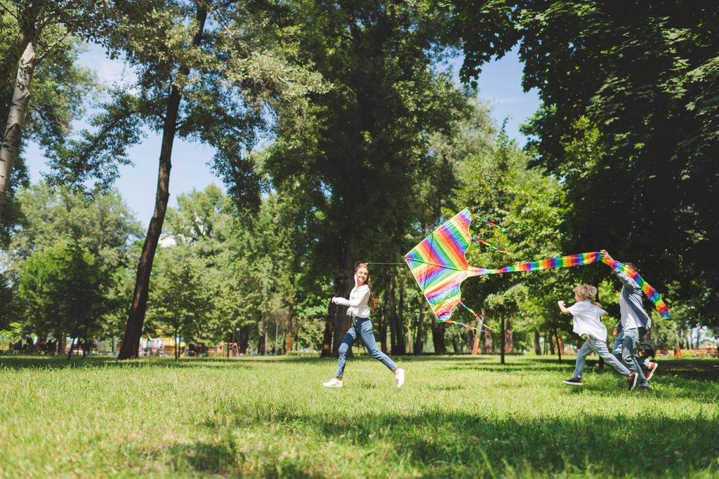 feliz familia corriendo y jugando con volando cometa en el parque con espacio de copia
 - Foto, imagen