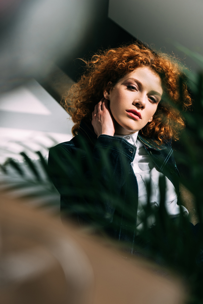 selective focus of stylish redhead girl posing near green leaves - Photo, Image