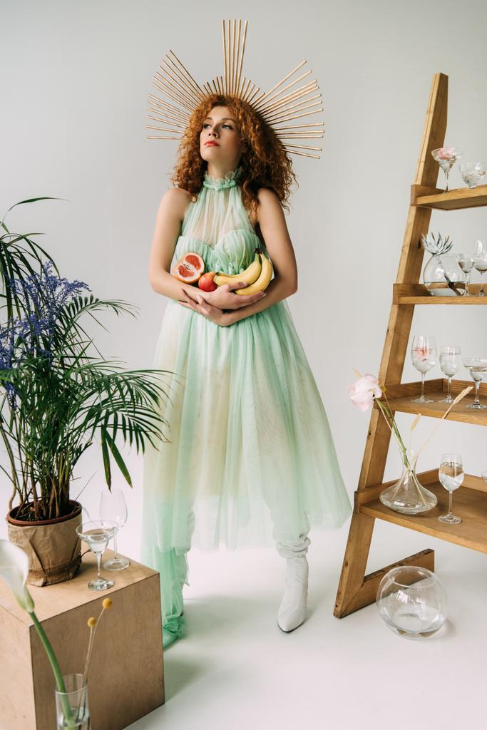 стильна дівчина з аксесуаром на голові та фруктами біля сходів з квітами та окулярами
 - Фото, зображення