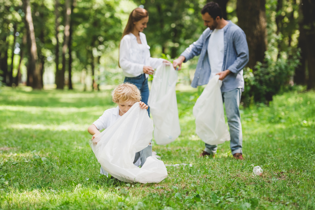 família pegando lixo em sacos de plástico no parque
 - Foto, Imagem