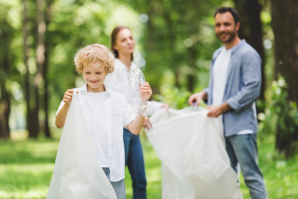 heureux famille ramasser les ordures dans des sacs en plastique dans le parc
 - Photo, image