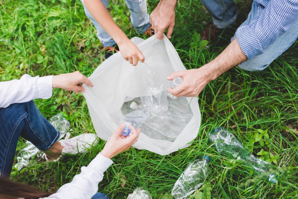 vista superior de la familia poniendo basura en bolsa de plástico en el parque
 - Foto, Imagen